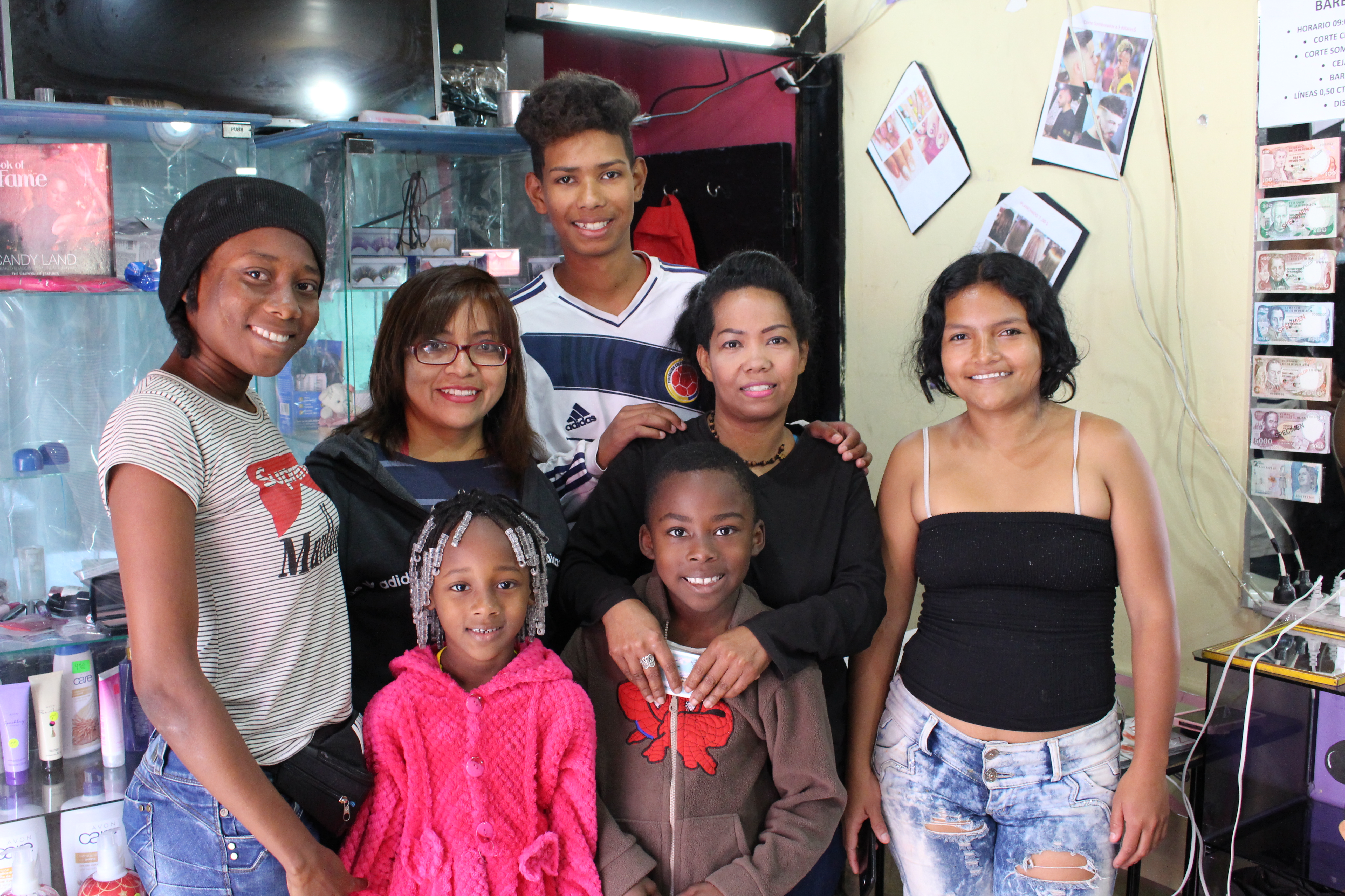 Monica (second from right), a Graduation participant, Colombian refugee, and entrepreneur, in her Salon with her three employees and their children, in Quito, Ecuador.